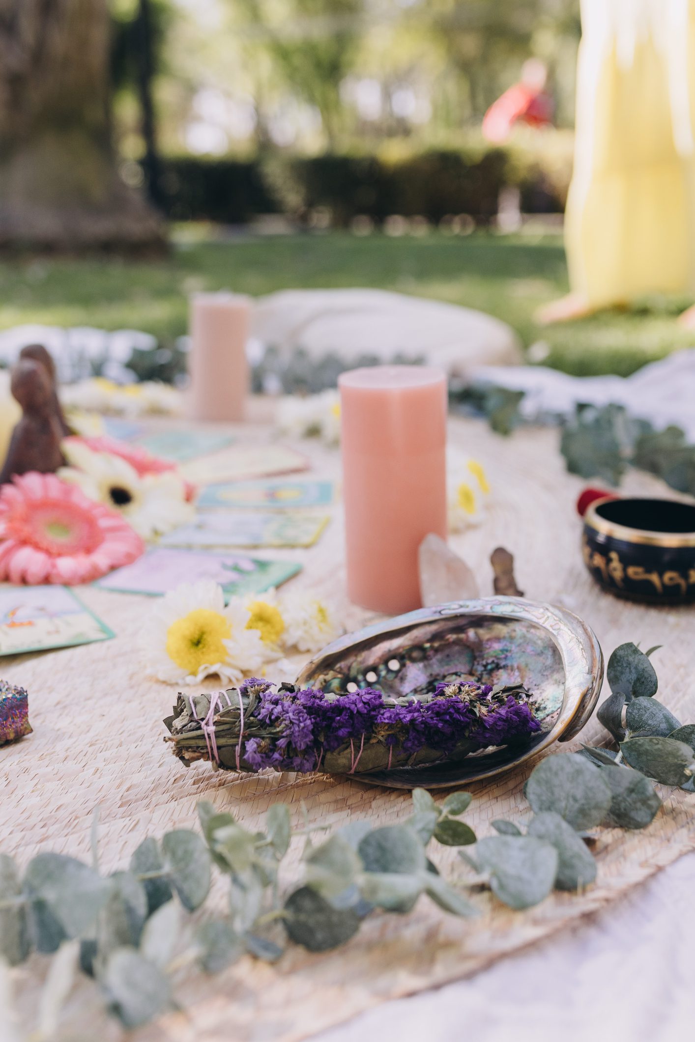 Mat spread on the grass with items to perform a ceremony, candles, quartz, flower, cards